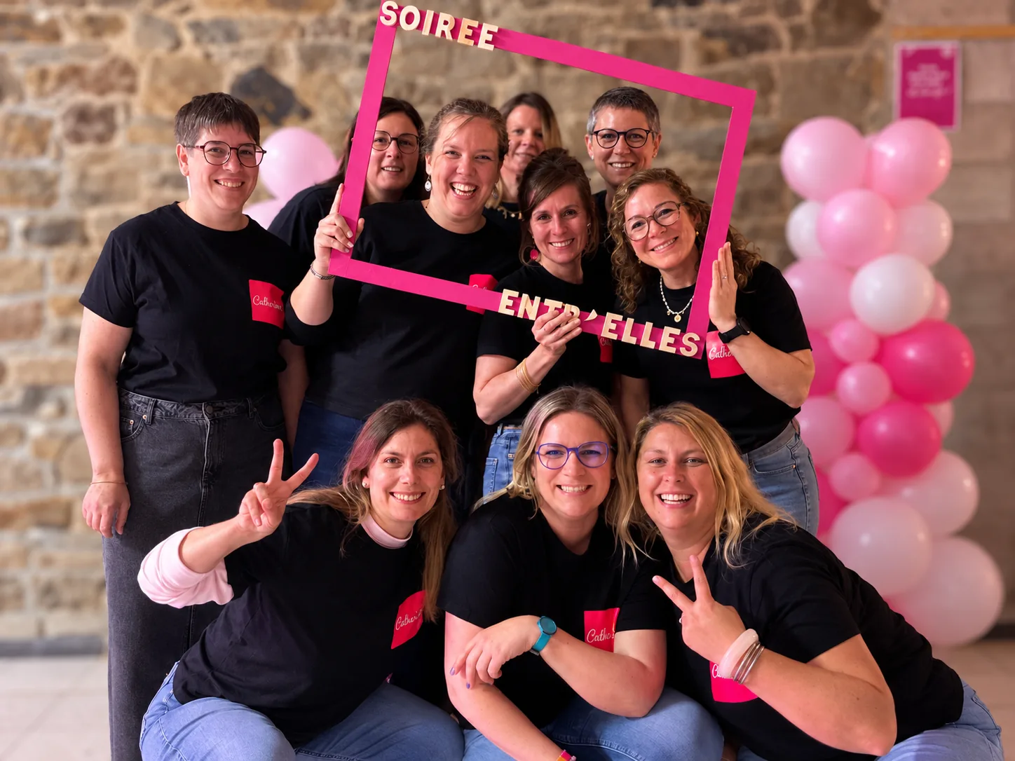 L'équipe de Cultur'elles.Bdv, souriante, autour d'un cadre photo rose « Soirée entr'Elles »