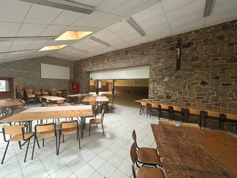 La salle avec son mur en pierre, tables et chaises en place